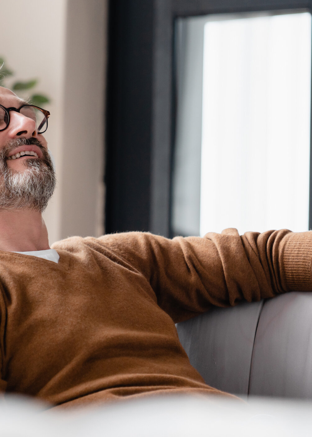 Entspannter Mann mit Kopfhörern auf Sofa, 7Mind App Integration, Wellness-Moment