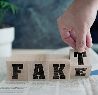 Vier Holzwürfel mit Buchstaben bilden ein Wort. Eine Hand bewegt den letzten Würfel, so dass man "Fake" oder "Fakt" lesen kann.