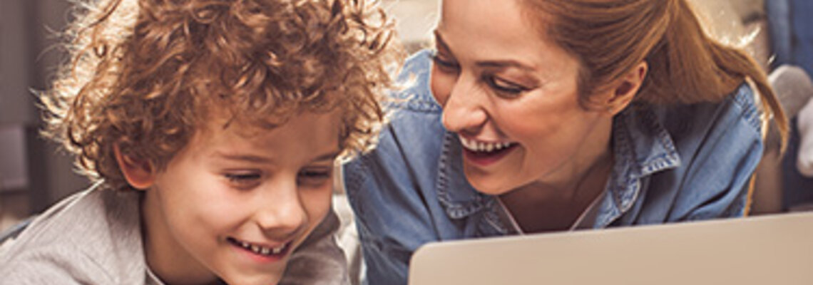 Frau und Junge sehen etwas auf dem Laptop an