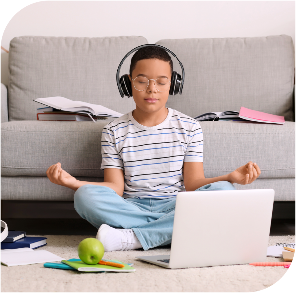 Junge mit Headphones meditiert vor Laptop