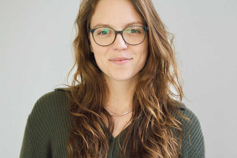 orträt von Juliane Meyer-Benz, Gastautorin bei BARMER Durchblickt, mit langen braunen Haaren und Brille vor hellem Hintergrund.