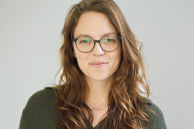 orträt von Juliane Meyer-Benz, Gastautorin bei BARMER Durchblickt, mit langen braunen Haaren und Brille vor hellem Hintergrund.