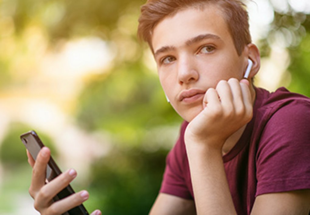 Nachdenklicher Junge mit Kopfhörern und Smartphone