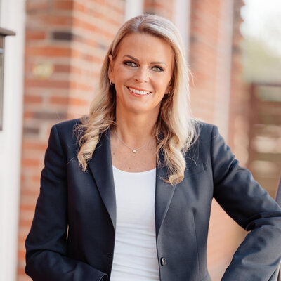 orträt von Silke Müller, Gastautorin bei BARMER Durchblickt, mit langen blonden Haaren und dunklem Blazer vor hellem Hintergrund.