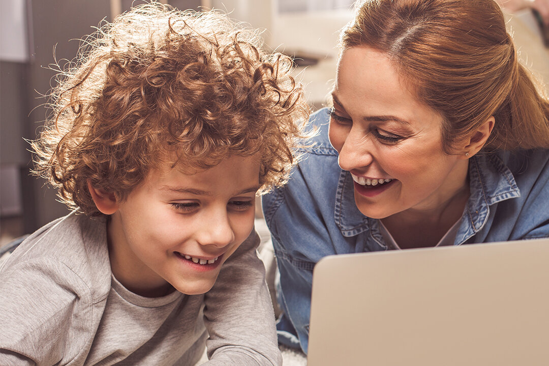 Frau und Junge sehen etwas auf dem Laptop an