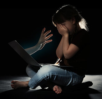 Kind vor Laptop, verdeckt das Gesicht, symbolisch für Online-Gefahren.
