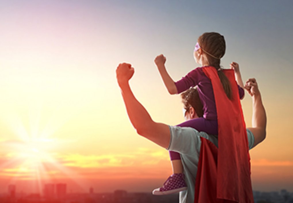 Mann mit Superheldencape trägt Mädchen mit Superheldencape auf den Schultern
