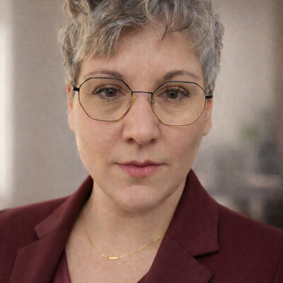 Porträt von Aline Sommer-Noack, Gastautorin bei BARMER Durchblickt, mit kurzen grauen Haaren und Brille vor unscharfem Hintergrund.