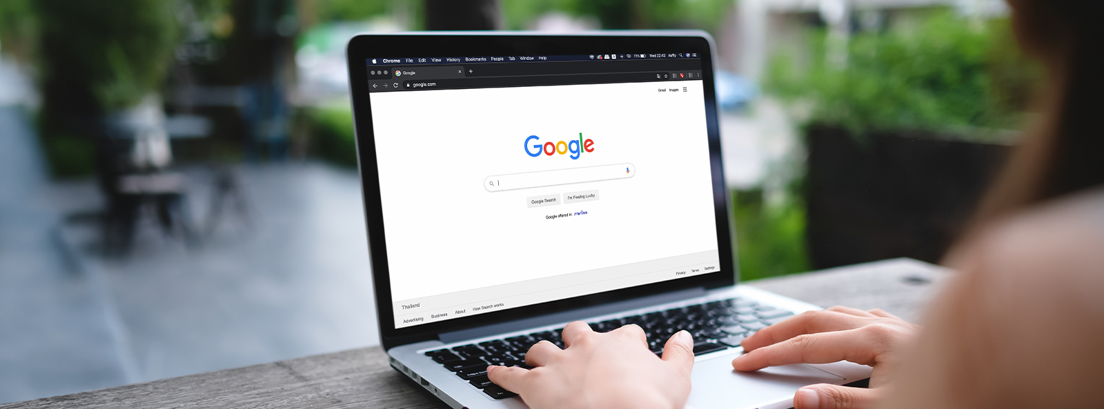 Hände auf Laptop-Tastatur mit geöffneter Google-Suchmaschine auf dem Bildschirm