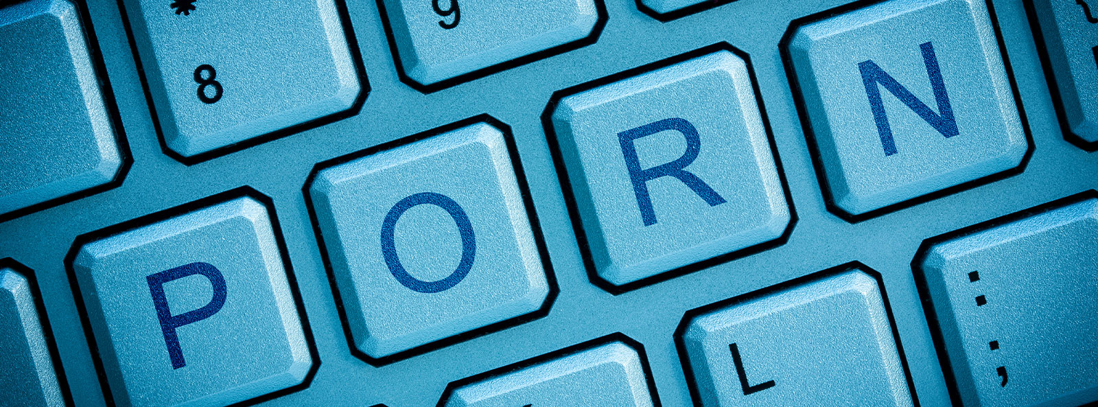 PORN-Schriftzug auf einer Computer-Tastatur in blauem Licht dargestellt.
