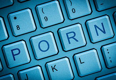 PORN-Schriftzug auf einer Computer-Tastatur in blauem Licht dargestellt.