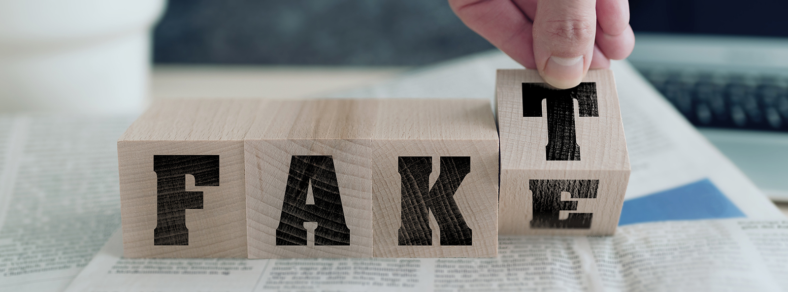 Vier Holzwürfel mit Buchstaben bilden ein Wort. Eine Hand bewegt den letzten Würfel, so dass man "Fake" oder "Fakt" lesen kann.