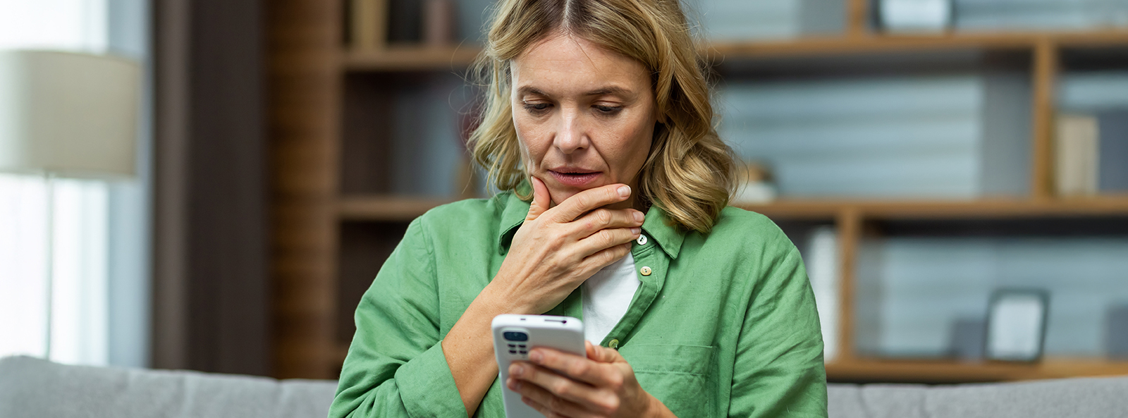 Frau schaut besorgt auf ein Smartphone.