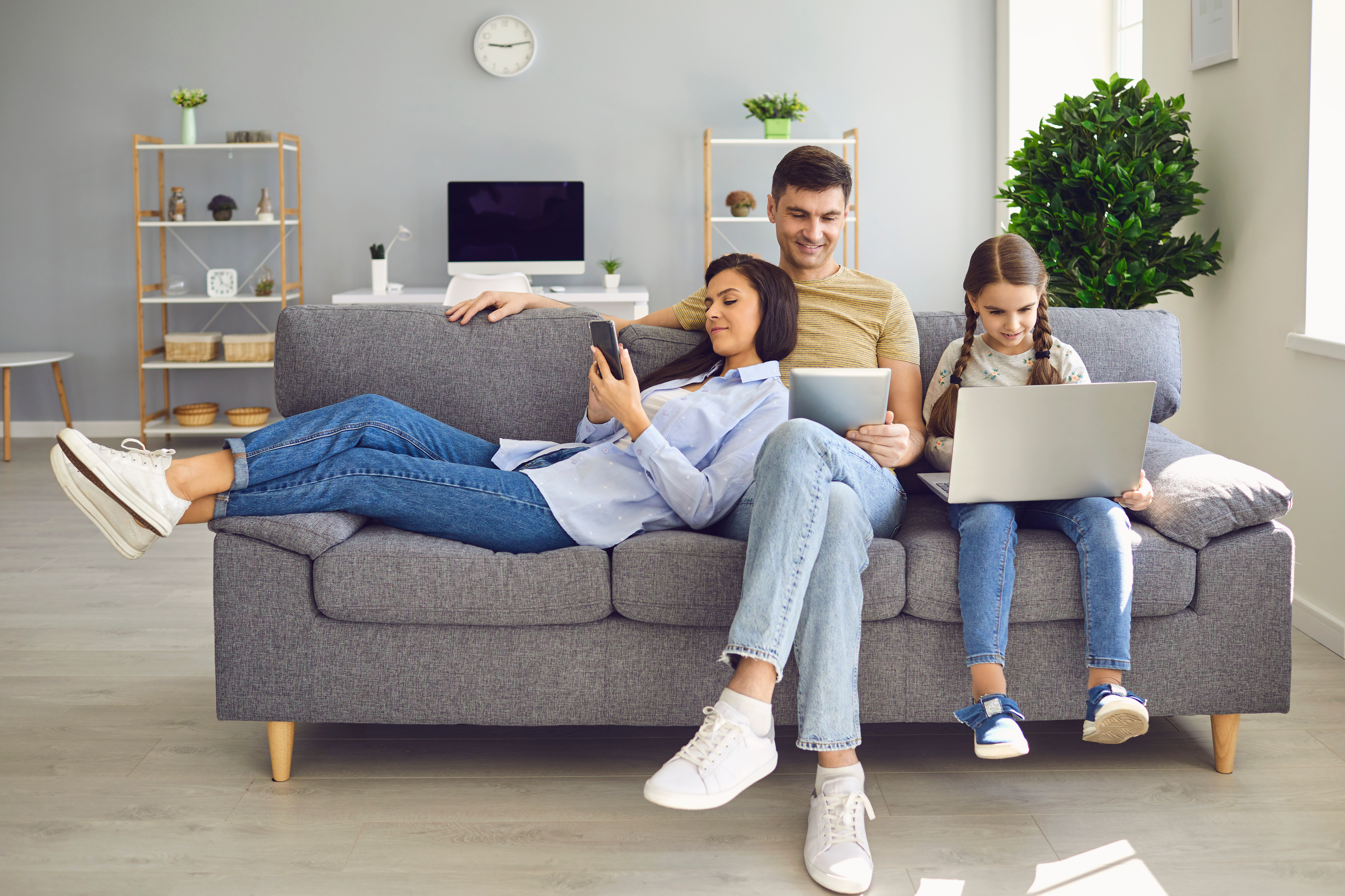 Familie mit mobilen Endgeräten auf Sofa