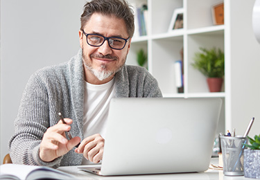 Mann sitzt vor Laptop