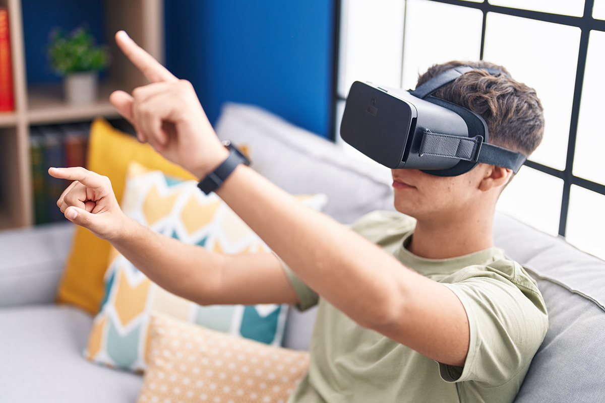 Junge mit VR-Brille macht in einem hellen Wohnzimmer Handbewegungen und ist in die virtuelle Umgebung vertieft.