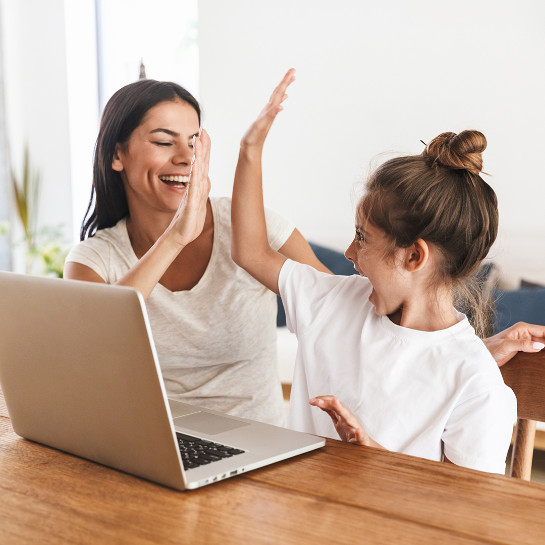  Eine Frau und ein Mädchen sitzen lachend an einem Laptop und geben sich ein High Fove BARMER-Durchblickt-artikel-eltern-wie-eltern-ihre-kinder-in-medienregeln-einbeziehen-header.jpg