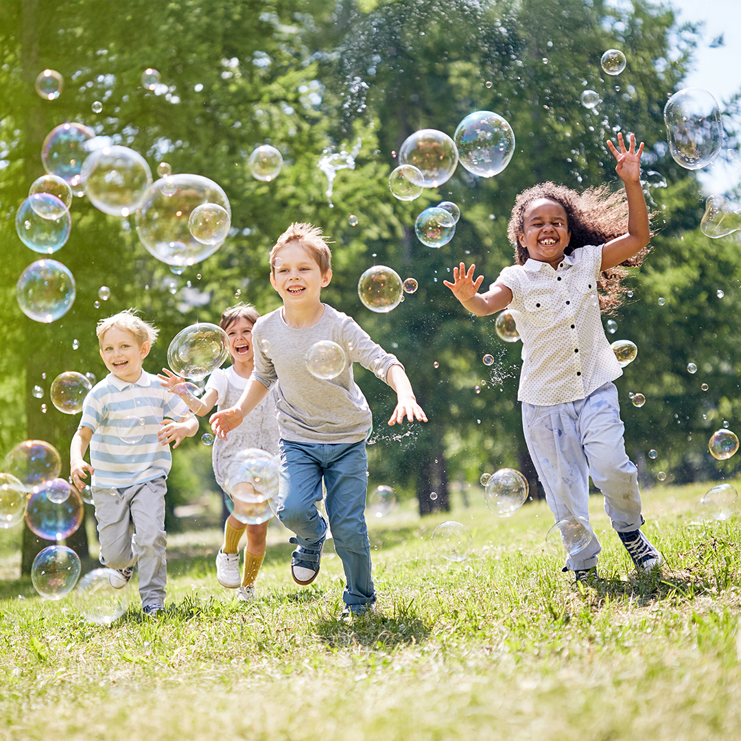 Vier Kinder rennen lachend über eine Wiese und spielen mit Seifenblasen.  20251215_DGK_Artikel-06_7Mind-Soft-Skills.jpg