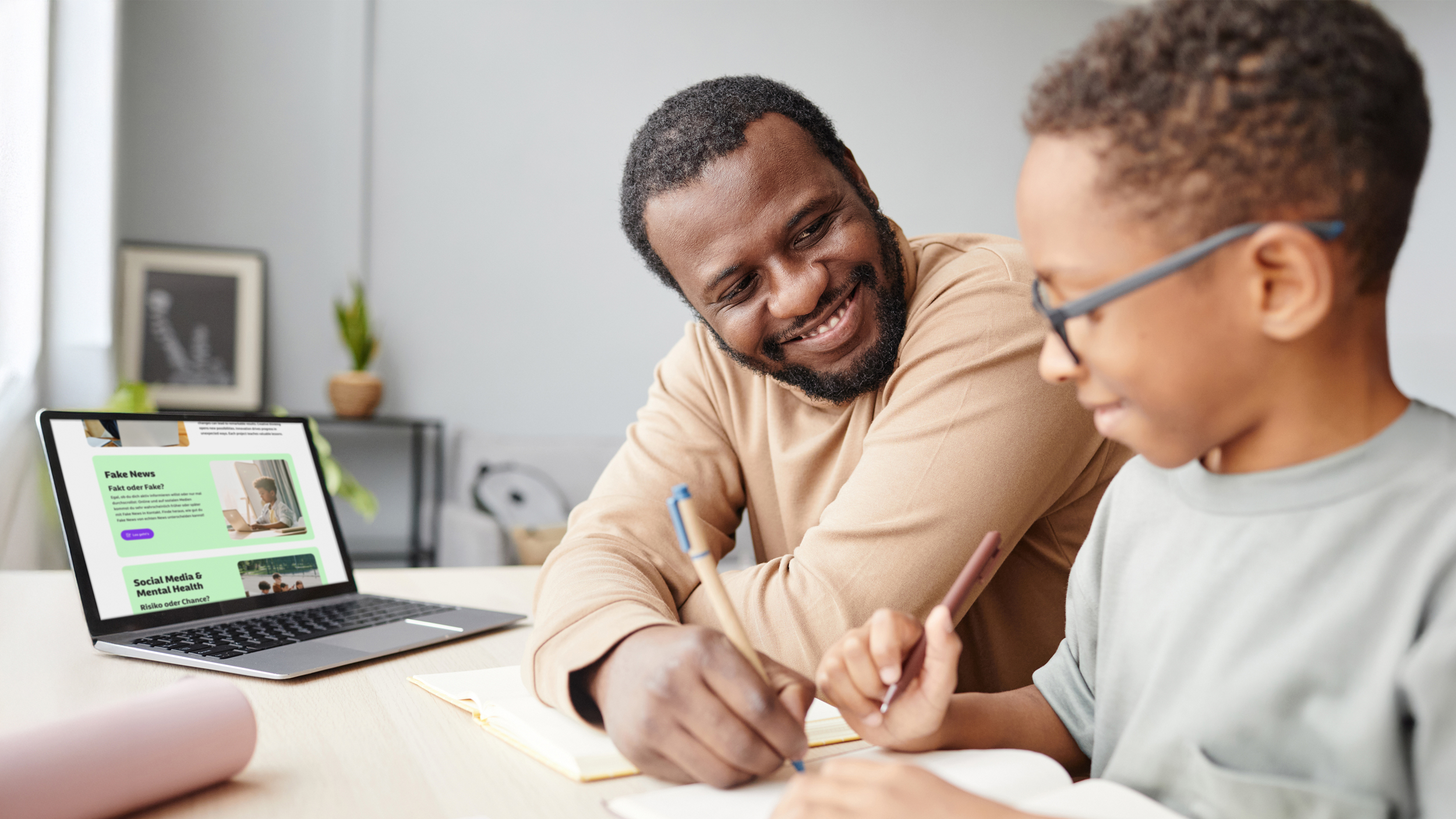 Vater und Kind mit Brille arbeiten gemeinsam am Laptop und mit Dokumenten – digitale Lernbegleitung, Eltern-Mentoring, Gesundheitskompetenz