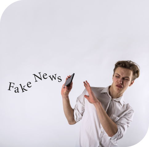 Junger Mann wehrt die fliegenden Buchstaben "Fake News" mit seinem Smartphone ab.