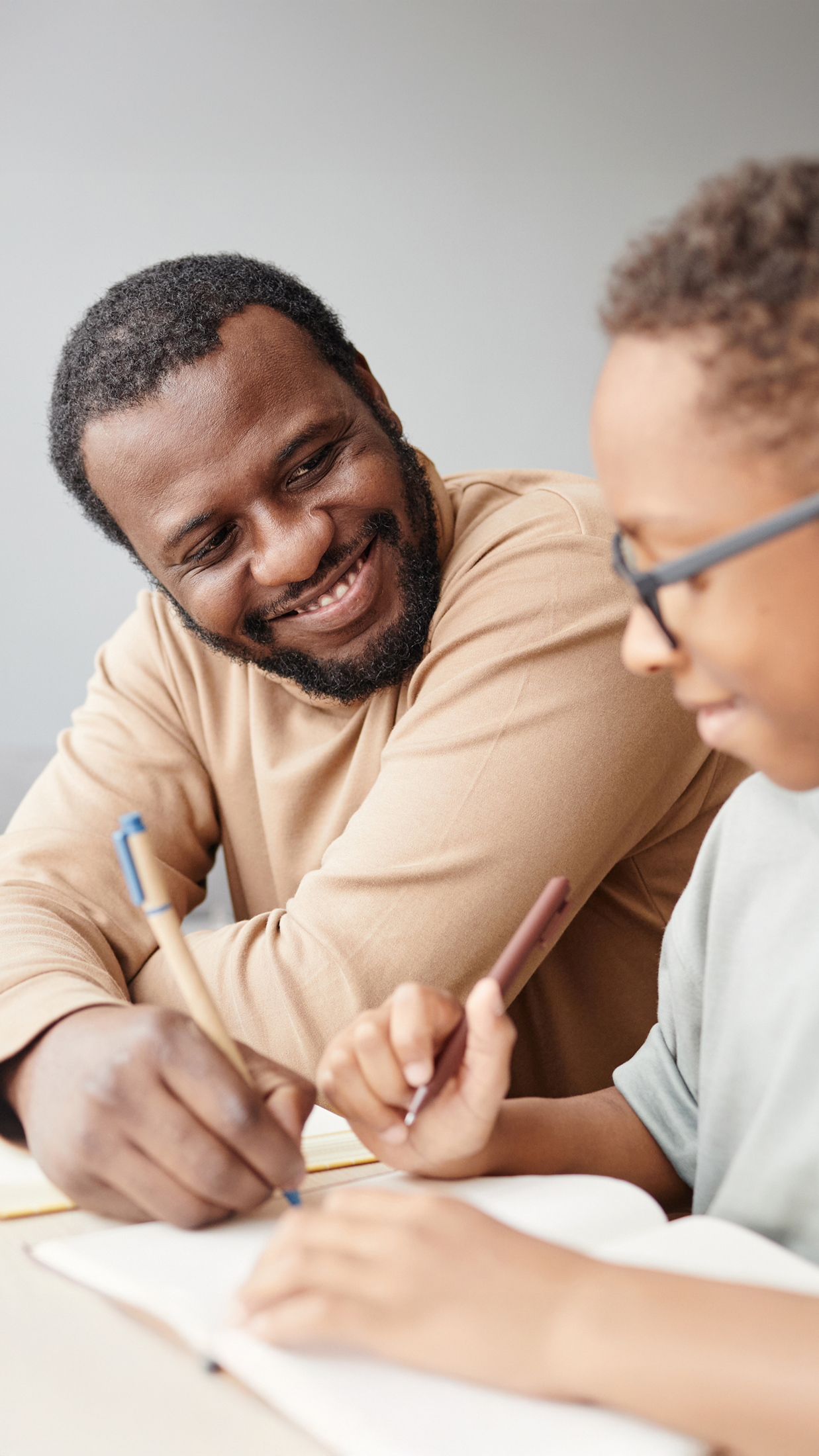 Erwachsener und Kind arbeiten gemeinsam an Dokumenten mit Stiften – digitale Unterstützung für Familien